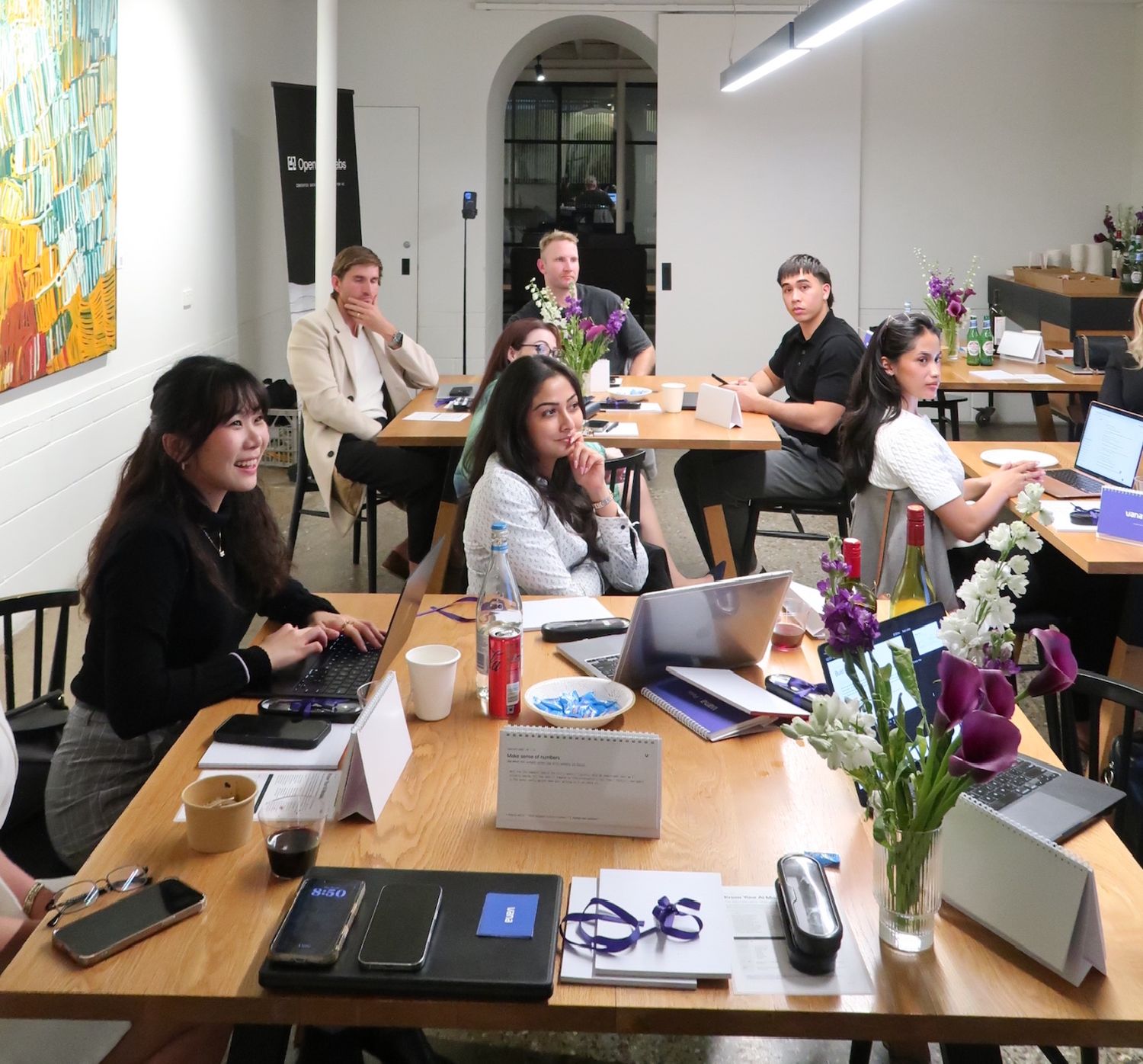 Guests working on laptops at long tables during the Brisbane session
